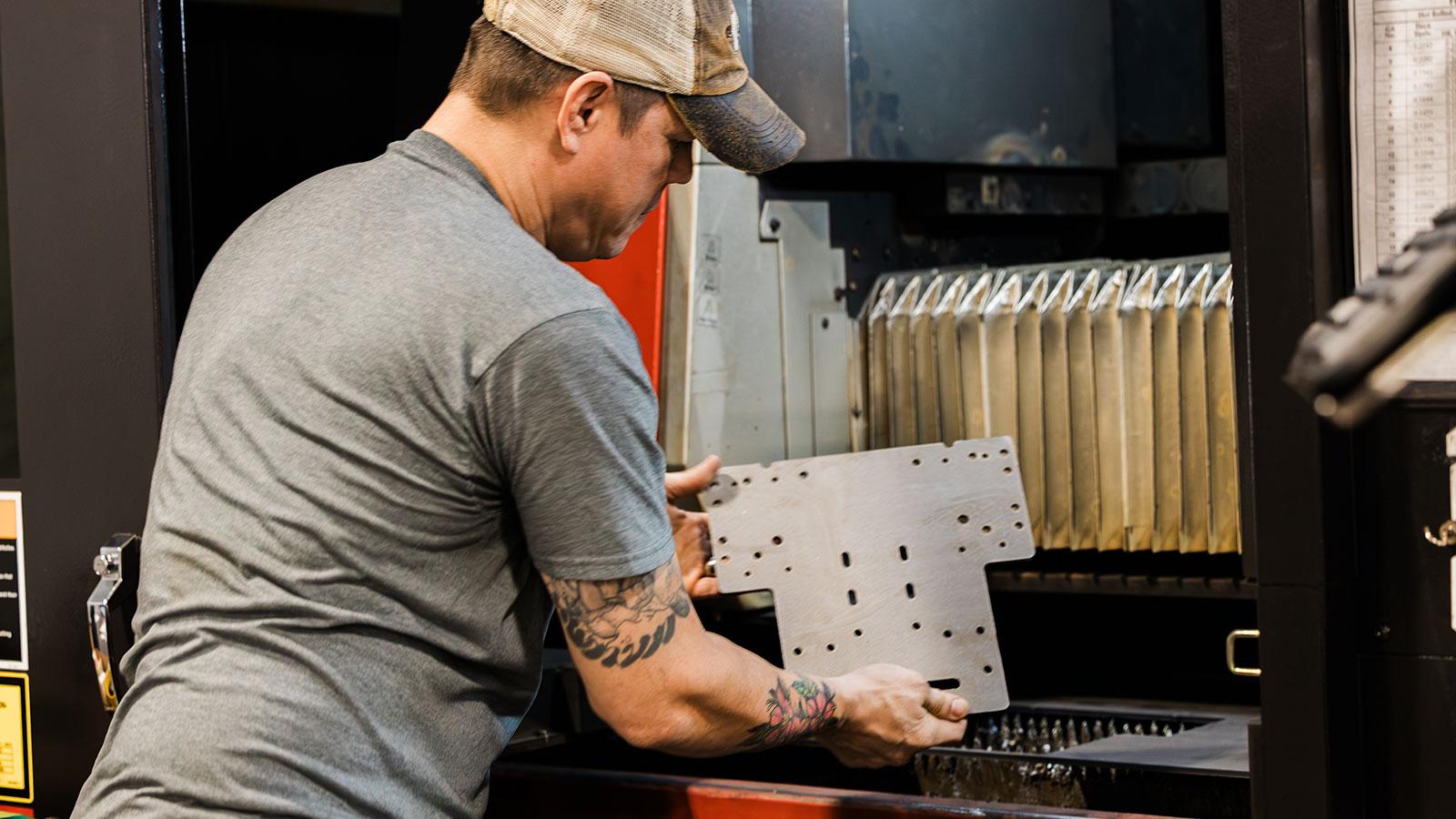 a JTD craftsman quality controlling a piece cut by the ENSIS AMADA Fiber laser.